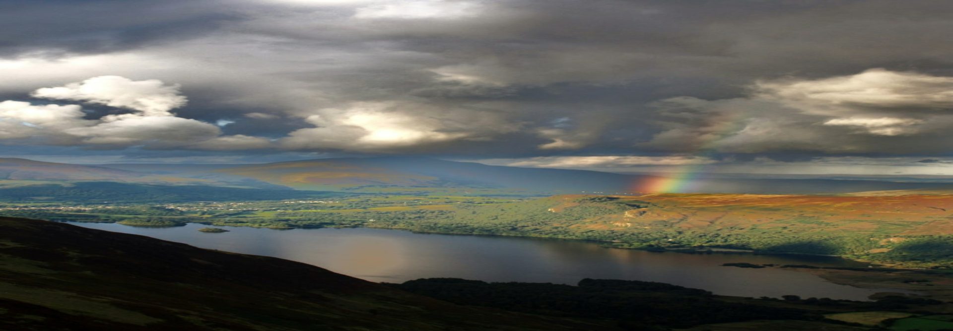 A rainbow in the sky over a lake.