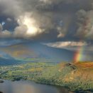A rainbow is seen over a lake and mountains.